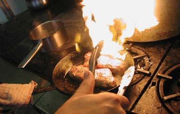 A chef cooking over flame in the Woods kitchen